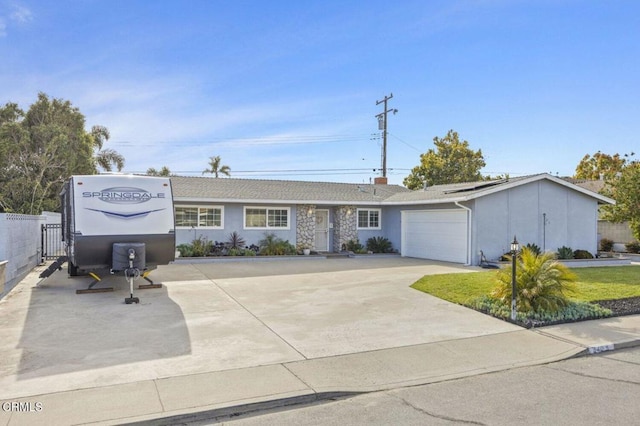 single story home with solar panels, an attached garage, fence, concrete driveway, and a front lawn