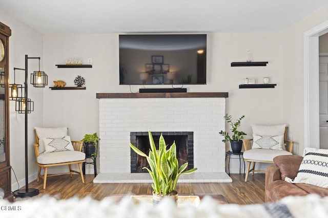 living area featuring a brick fireplace, baseboards, and wood finished floors