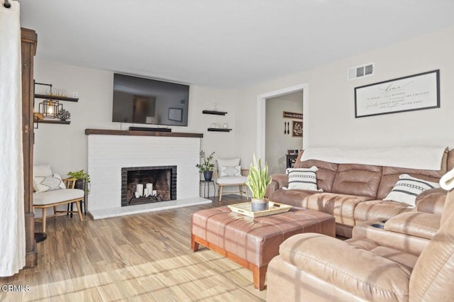 living area with visible vents, wood finished floors, and a fireplace