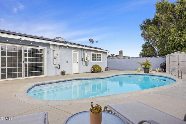 view of pool featuring a fenced in pool, an outdoor structure, a shed, a patio area, and a fenced backyard