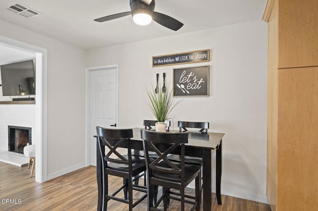 dining area with visible vents, baseboards, wood finished floors, and ceiling fan