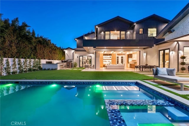 back of property featuring a balcony, outdoor dry bar, french doors, and a lawn