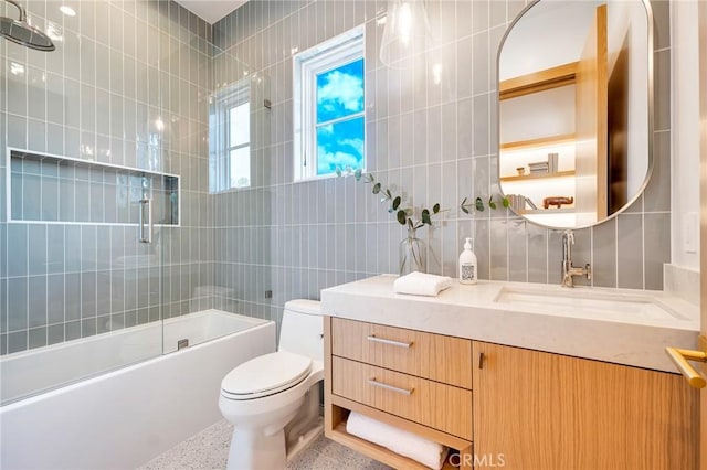 full bath featuring toilet, vanity, speckled floor, and tile walls