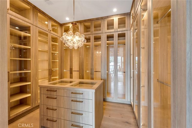 spacious closet featuring a notable chandelier and light wood-style floors