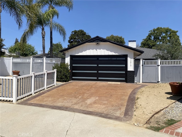 garage featuring a gate, fence, and driveway