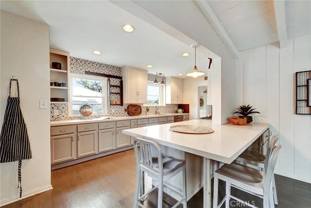 kitchen with a breakfast bar area, backsplash, light wood-style floors, and light countertops