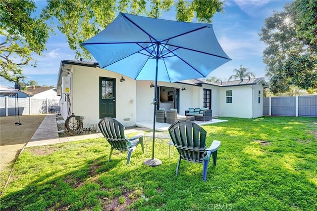 rear view of house featuring an outdoor living space, a fenced backyard, stucco siding, a yard, and a patio