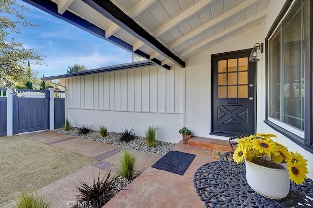 property entrance with a gate, board and batten siding, and fence