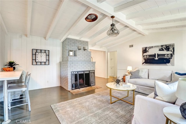 living room featuring visible vents, wood finished floors, lofted ceiling with beams, and a brick fireplace