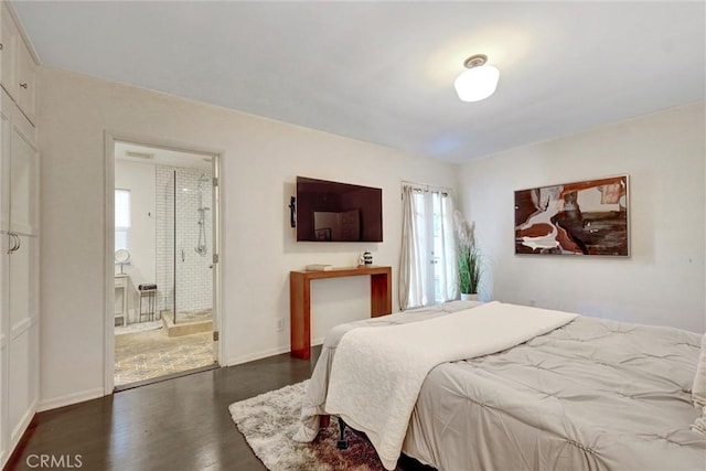 bedroom with connected bathroom, wood finished floors, and baseboards