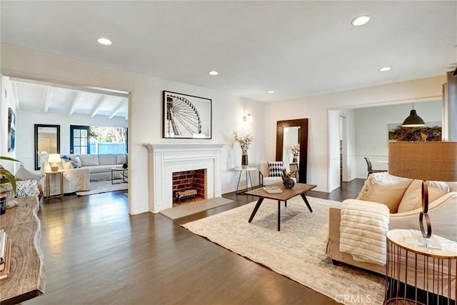 living area with dark wood-style floors, recessed lighting, beamed ceiling, and a fireplace with flush hearth