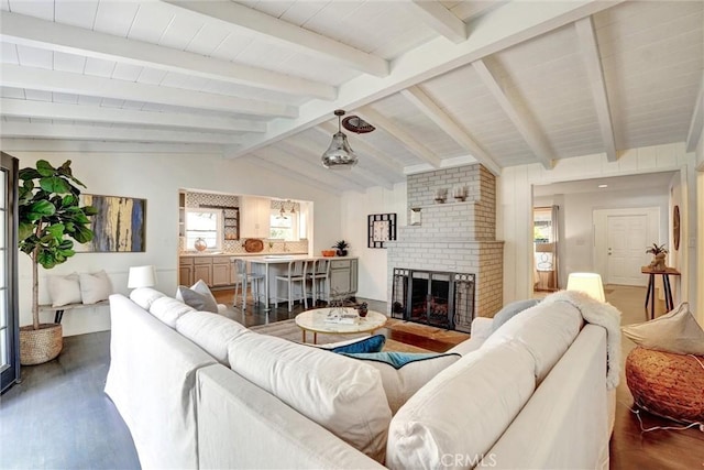 living area featuring lofted ceiling with beams, dark wood-style flooring, and a brick fireplace