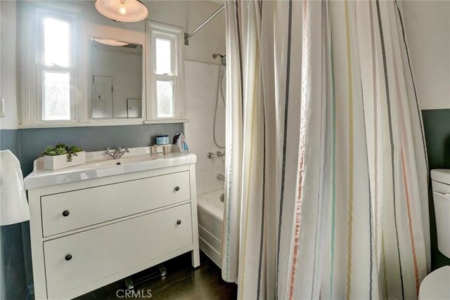 full bathroom featuring toilet, shower / bath combination with curtain, vanity, and plenty of natural light