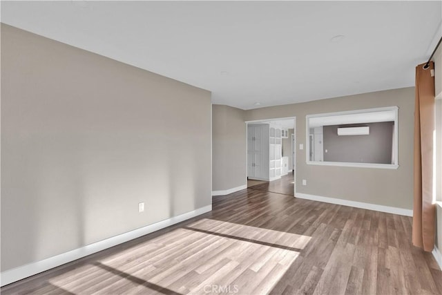 17908 Birch St, Hesperia, CA 92345 - empty room with an AC wall unit, baseboards, and wood finished floors