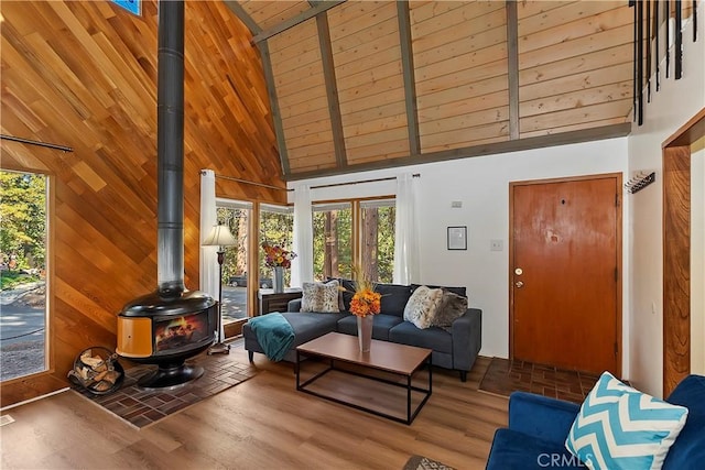 living room featuring wooden ceiling, a wood stove, wood finished floors, and high vaulted ceiling
