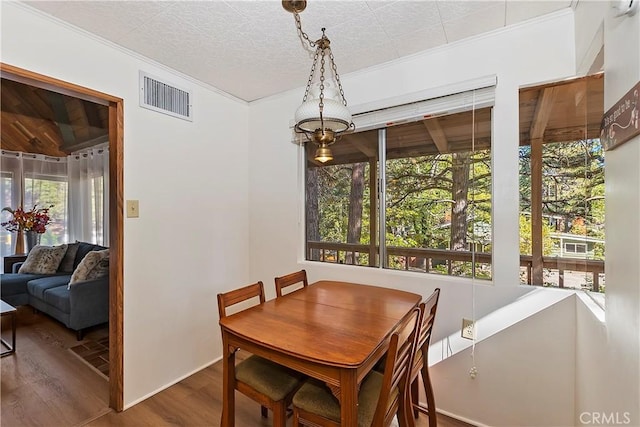 dining room with crown molding, wood finished floors, visible vents, and a textured ceiling