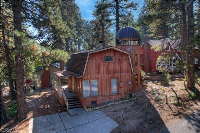 exterior space with a shingled roof and a gambrel roof