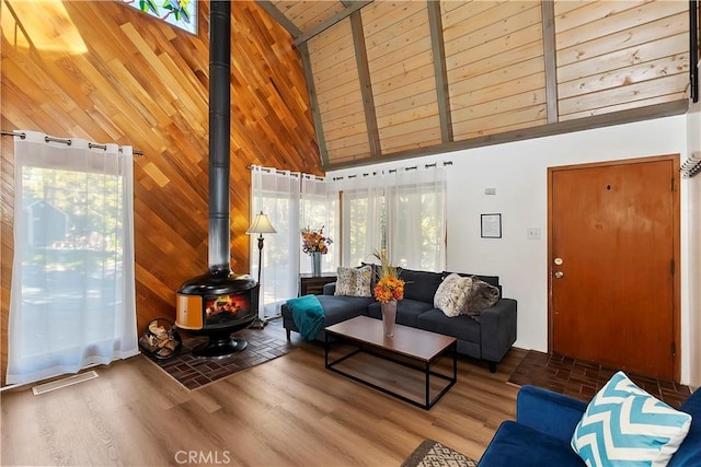 living room with wooden ceiling, a wood stove, wood finished floors, and high vaulted ceiling