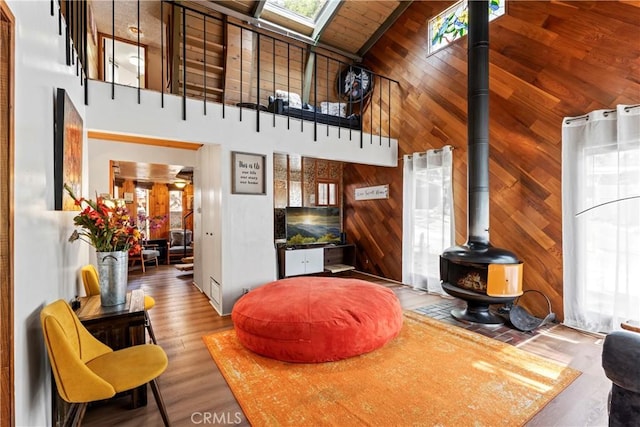 31867 Wagon Wheel Dr, Running Springs, CA 92382 - living room featuring a towering ceiling, a wood stove, wood walls, wood finished floors, and a skylight