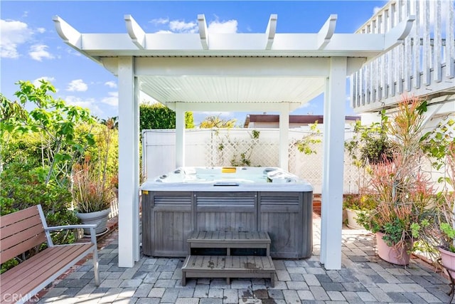 view of patio / terrace featuring fence and a hot tub