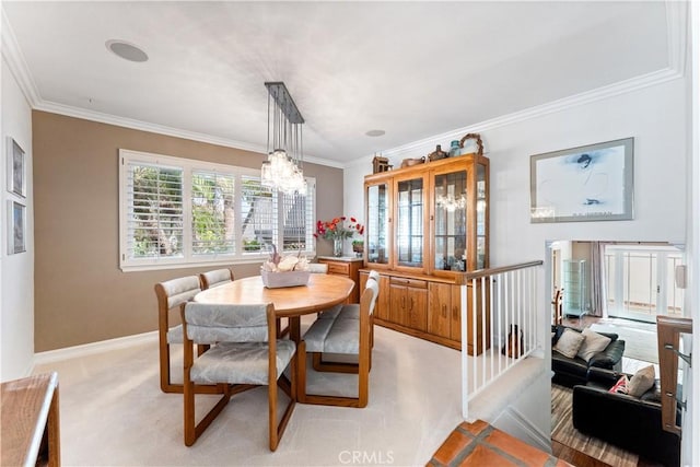 dining room featuring baseboards, a notable chandelier, ornamental molding, and carpet