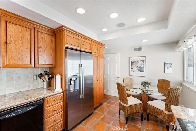 kitchen featuring tasteful backsplash, visible vents, stainless steel fridge, black dishwasher, and brown cabinetry