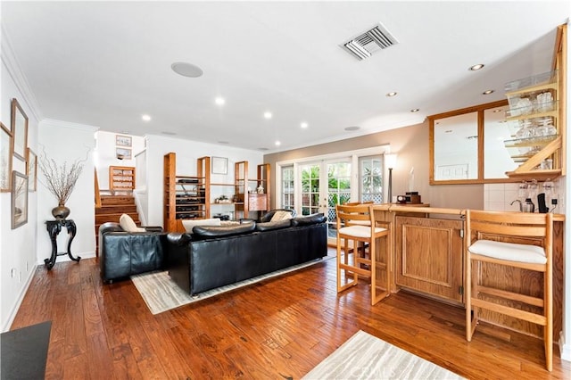 living area featuring visible vents, crown molding, stairs, bar, and wood-type flooring
