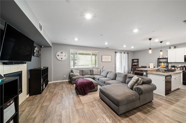 living room with light wood-style flooring, baseboards, visible vents, and recessed lighting