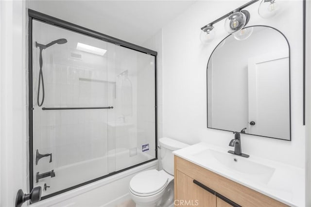 bathroom featuring vanity, combined bath / shower with glass door, and toilet