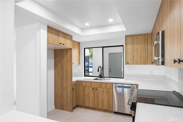 kitchen with recessed lighting, light countertops, a raised ceiling, a sink, and appliances with stainless steel finishes