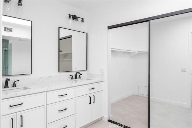 full bath featuring visible vents, a sink, double vanity, and a spacious closet