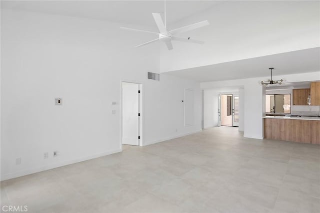 1910 Grand Bahama Dr E, Palm Springs, CA 92264 - unfurnished living room with a towering ceiling, a ceiling fan, a chandelier, and baseboards
