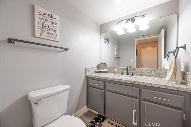 bathroom featuring toilet, vanity, baseboards, and visible vents