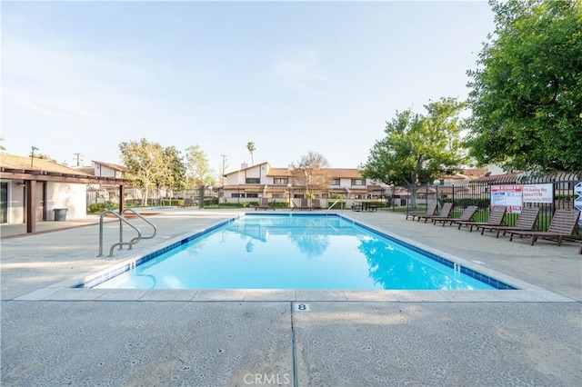 pool with a patio area and fence