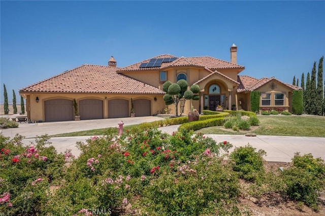 20711 Canyon Rd, Los Banos, CA 93635 - mediterranean / spanish-style house with a chimney, concrete driveway, an attached garage, a tile roof, and solar panels