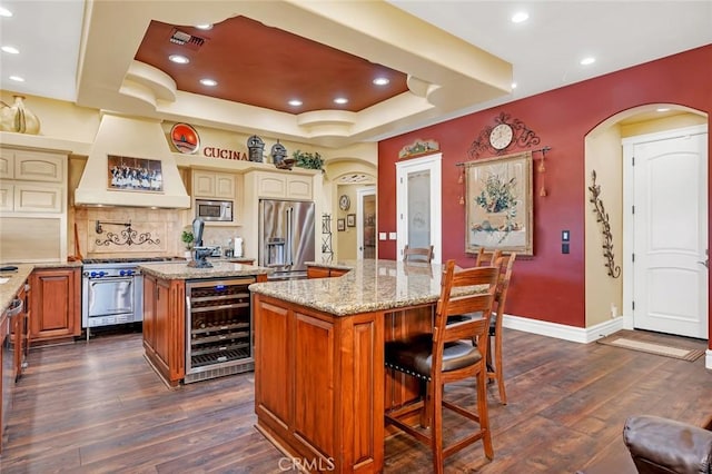 20711 Canyon Rd, Los Banos, CA 93635 - kitchen featuring a center island, wine cooler, arched walkways, high quality appliances, and premium range hood