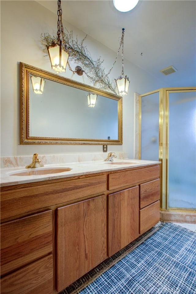 full bath featuring double vanity, visible vents, a stall shower, and a sink