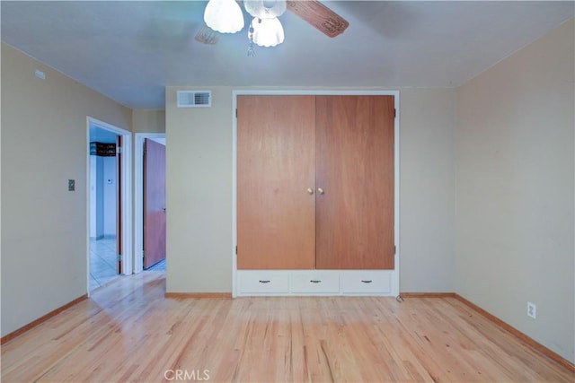 unfurnished bedroom featuring baseboards, wood finished floors, visible vents, and a closet