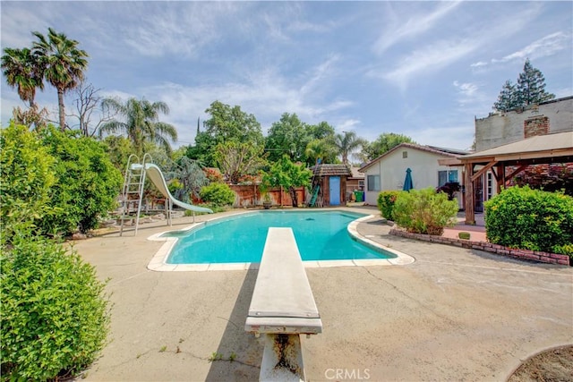 view of pool with a fenced in pool, a diving board, a water slide, a patio area, and a gazebo