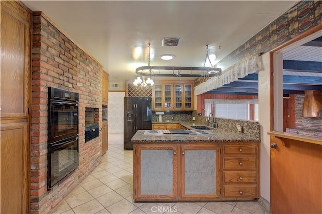 kitchen with light tile patterned floors, a sink, black appliances, a peninsula, and glass insert cabinets
