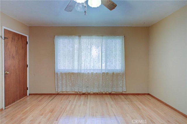 empty room featuring baseboards, wood finished floors, a wealth of natural light, and ceiling fan