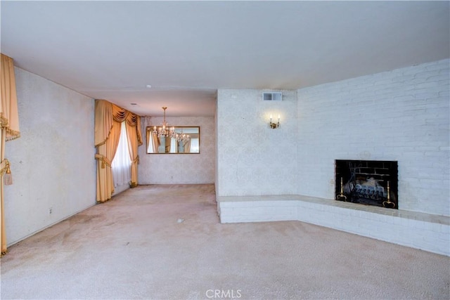 unfurnished living room featuring visible vents, a brick fireplace, carpet, and a chandelier