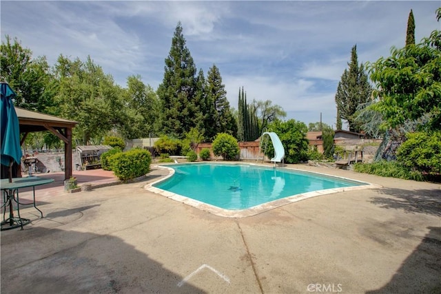 pool with fence, a patio area, a diving board, and a water slide