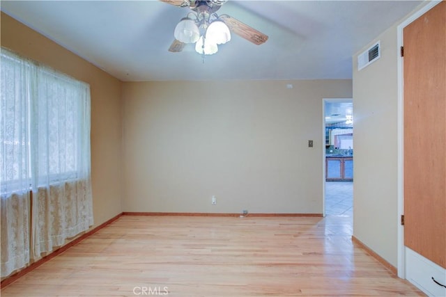 empty room with light wood-type flooring, baseboards, a ceiling fan, and visible vents