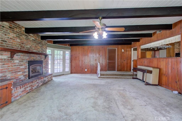 unfurnished living room with carpet floors, beam ceiling, wooden walls, and a fireplace