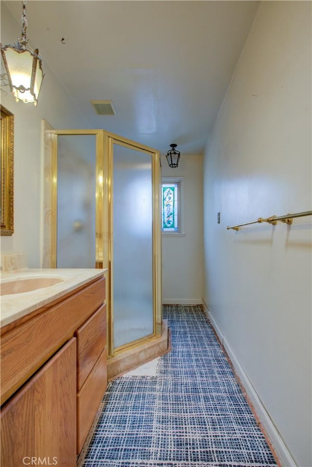 bathroom featuring baseboards, vanity, visible vents, and a stall shower