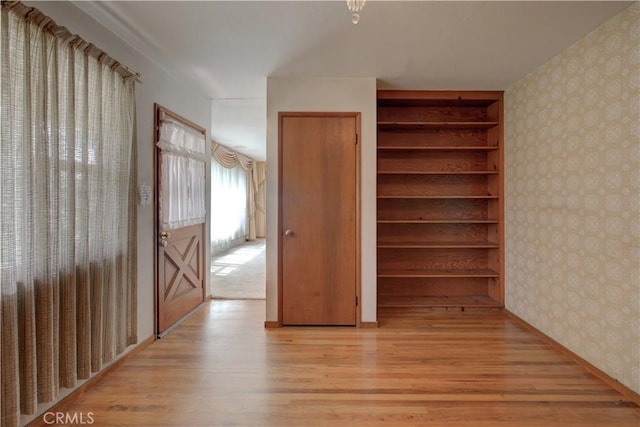unfurnished bedroom with wallpapered walls and light wood-type flooring