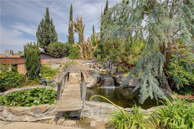 surrounding community featuring a small pond and fence
