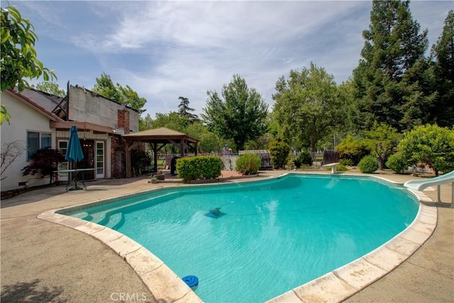 pool featuring a gazebo, a patio area, a diving board, and a water slide
