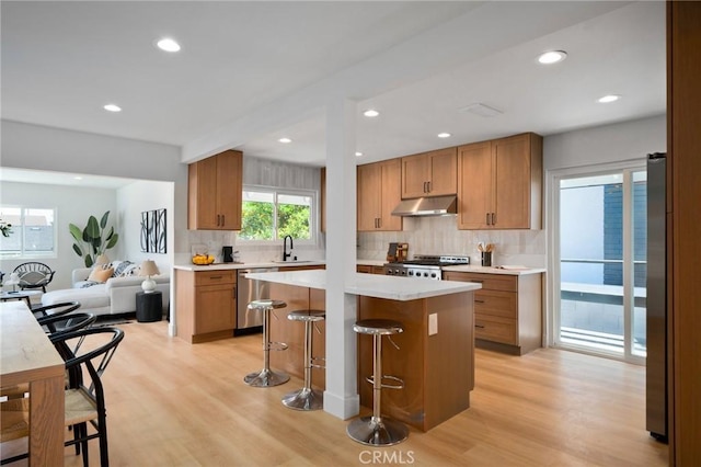 3130 E Craig Dr, Orange, CA 92869 - kitchen featuring stainless steel appliances, under cabinet range hood, decorative backsplash, a kitchen bar, and recessed lighting